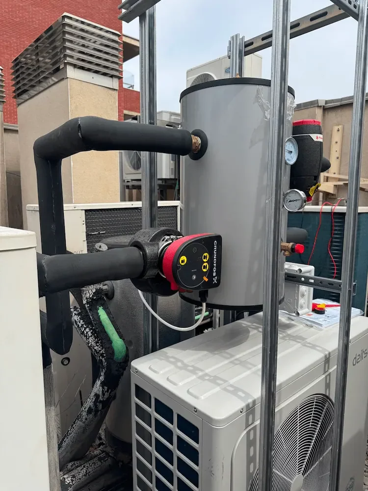 Depósito de inercia de aerotermia con bomba circuladora Grundfos y tuberías aisladas.