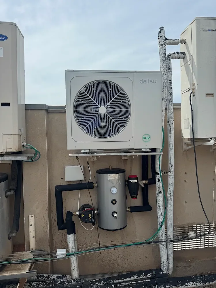 Sistema de aerotermia Deitsu con unidad exterior y conexiones hidráulicas en instalación técnica.